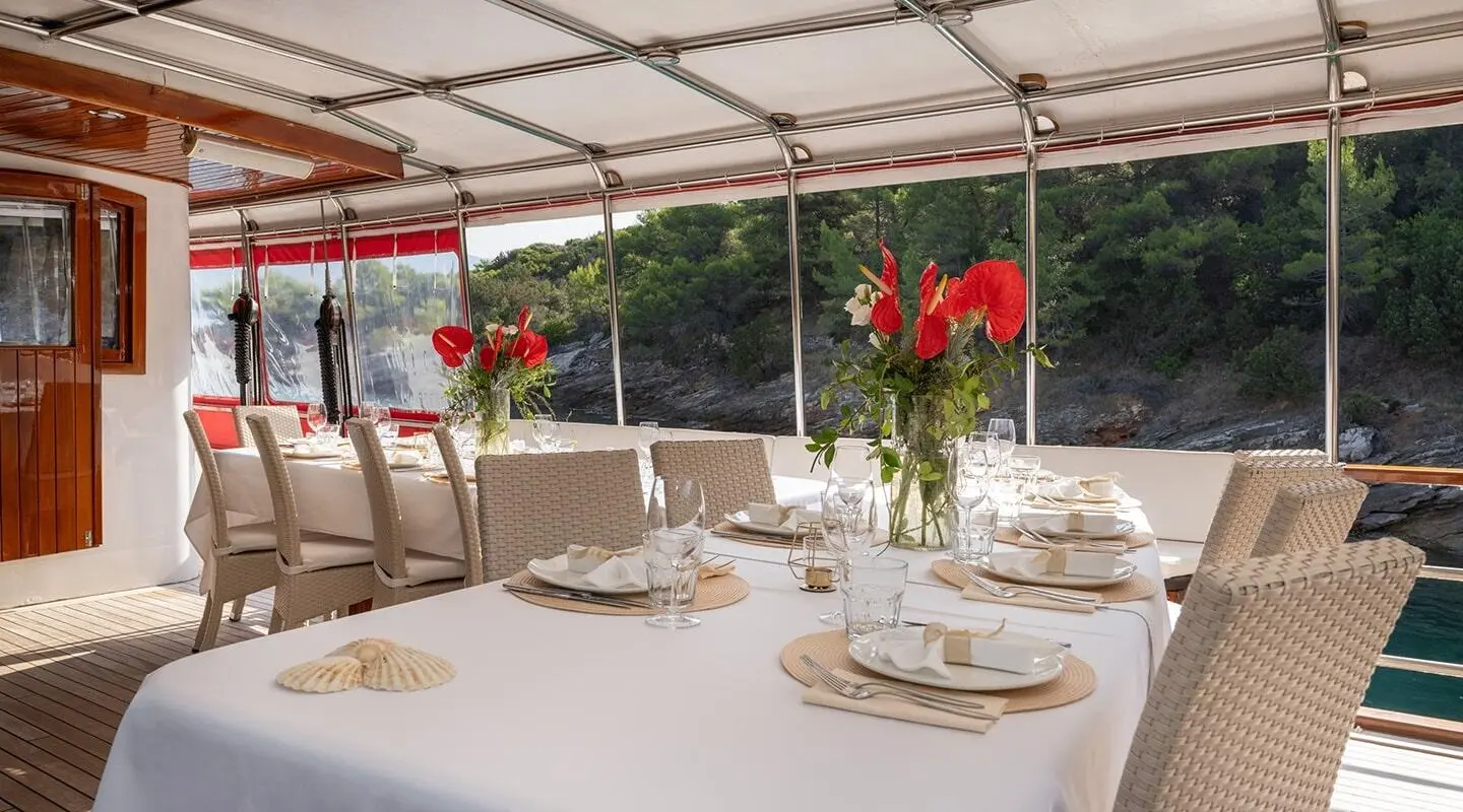 Barbara yacht dining table set for guests on outdoor deck at sunset