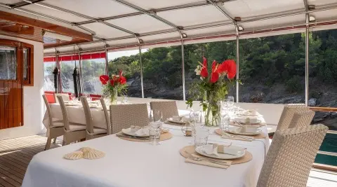 Barbara yacht dining table set for guests on outdoor deck at sunset