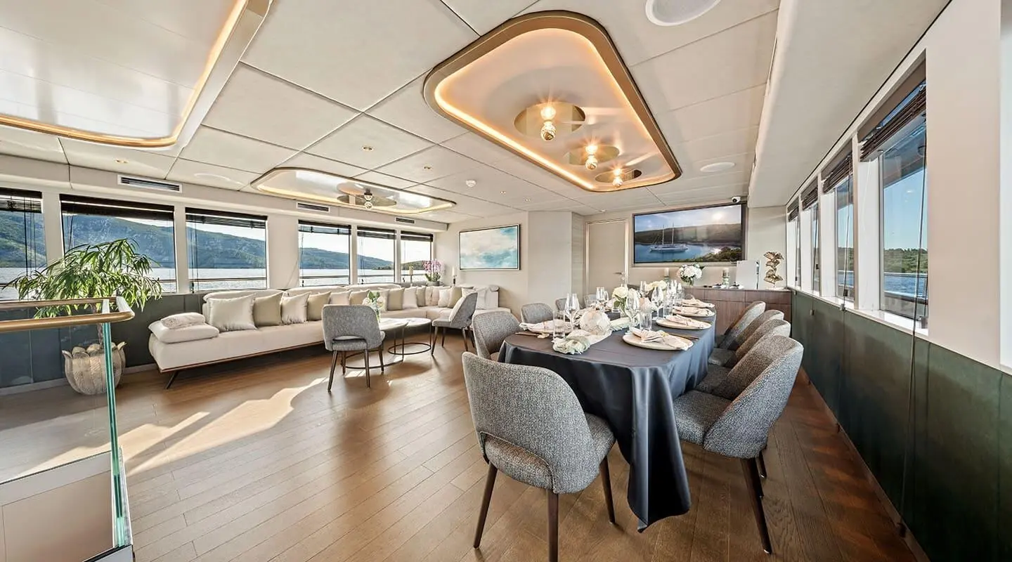 Anima Maris yacht interior dining area with table, seating, and warm lighting