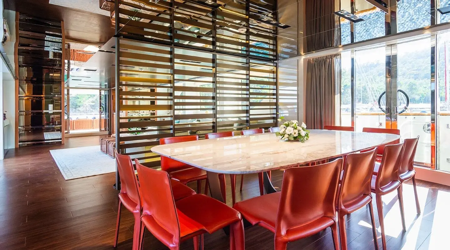 Takara One yacht dining area with wooden slat walls and red chairs around a long table