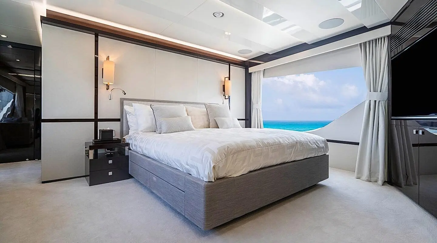 Queen-size bed in a bright yacht cabin with sea view through large window