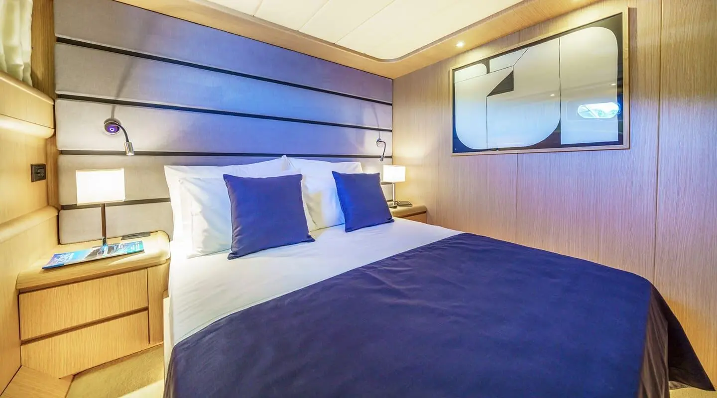 Phantom yacht cabin with blue bedspread, white linens, and blue accent pillows