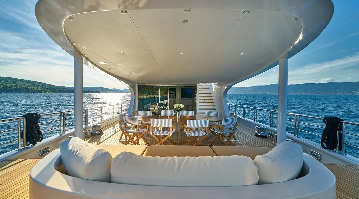 Deck dining area on Acapella yacht with chairs and table setup overlooking ocean