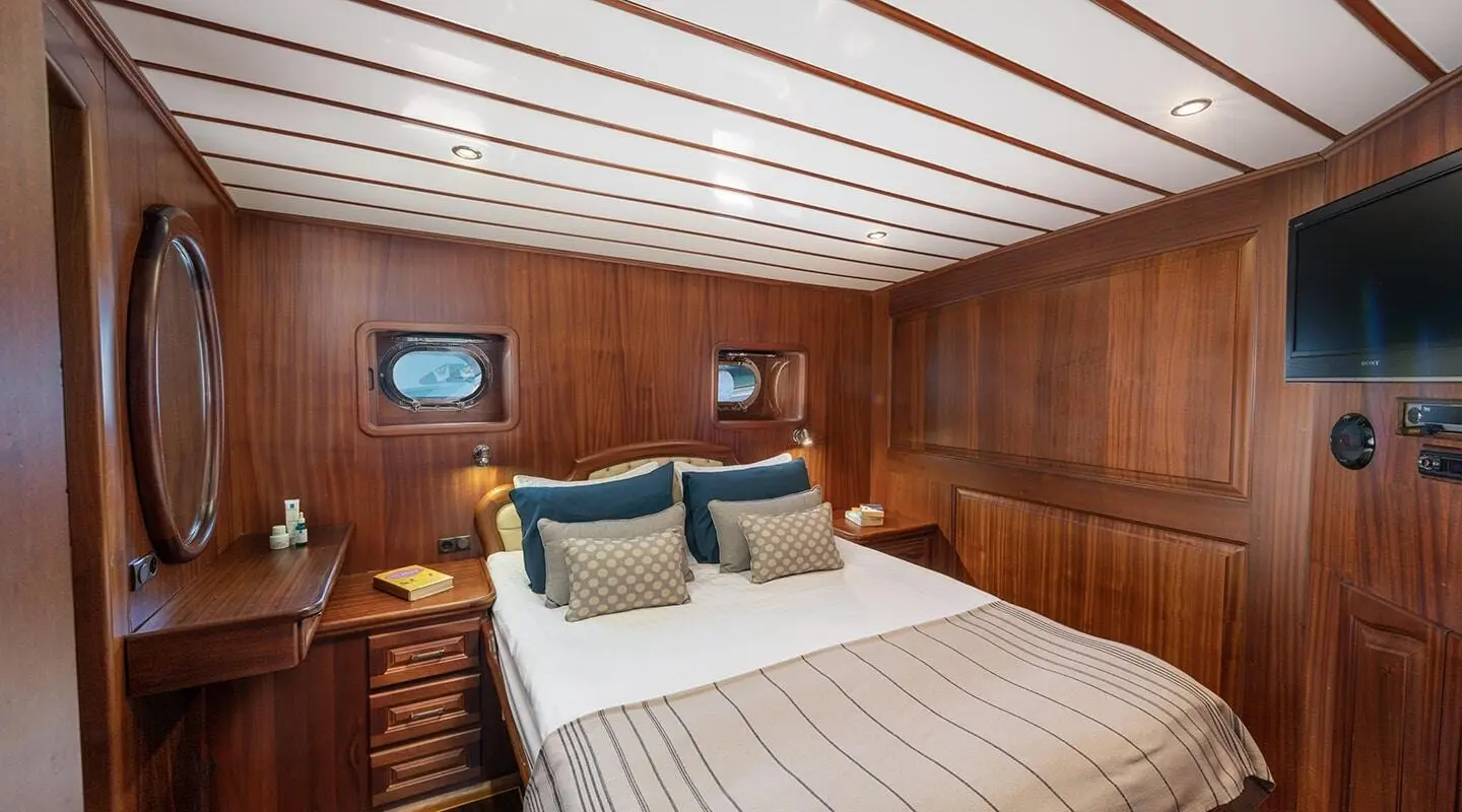 Sultan-class yacht cabin with striped ceiling, wooden walls, bed and pillows