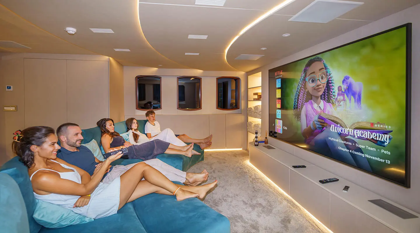 Maia yacht cinema lounge with people watching a large wall screen