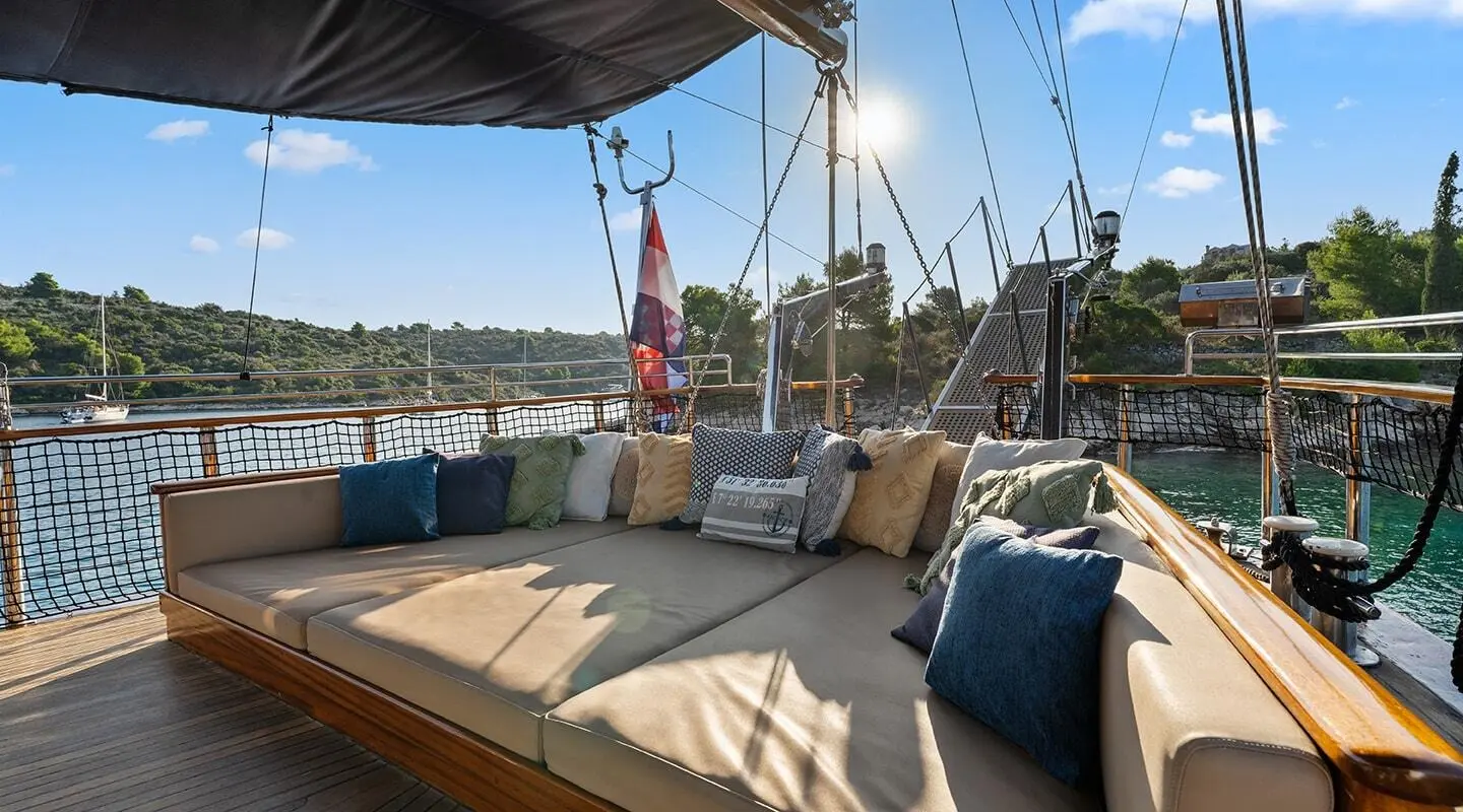 Smart Spirit yacht deck with cushioned seating, sunlit harbor, and blue sea