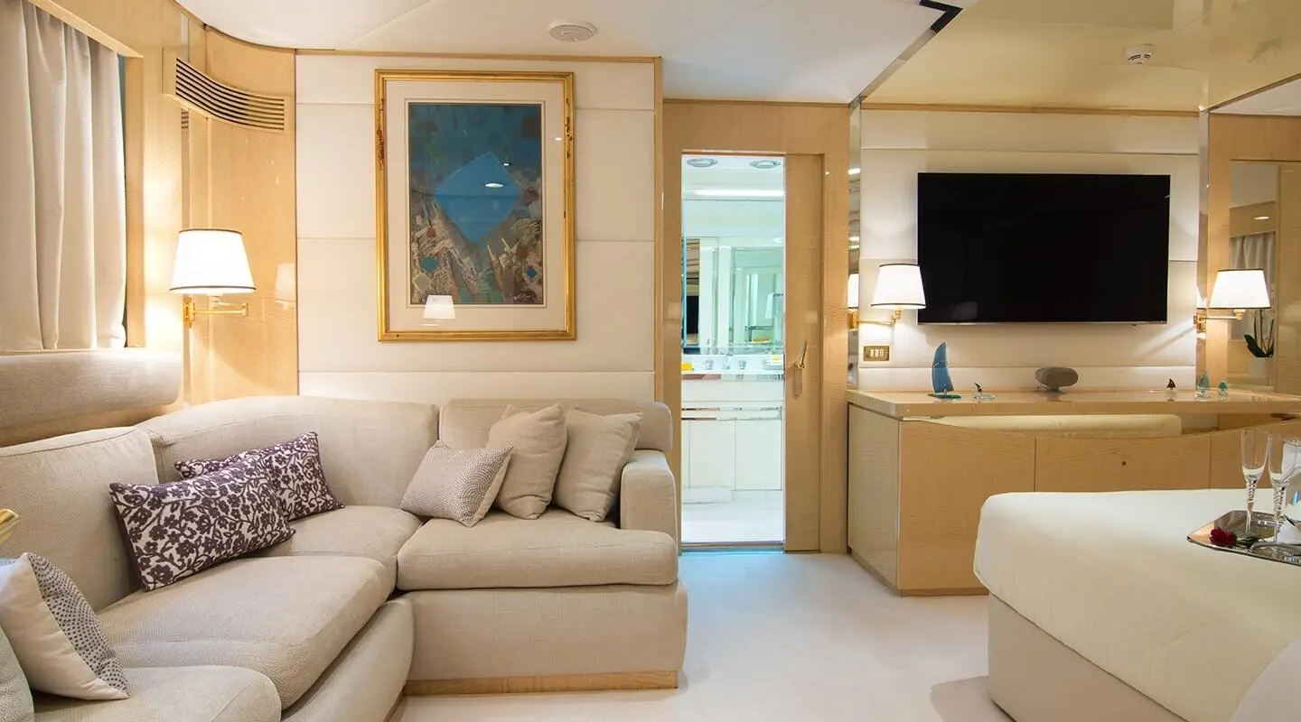 Luxurious yacht interior with beige couch, wooden cabinets, and flat screen TV