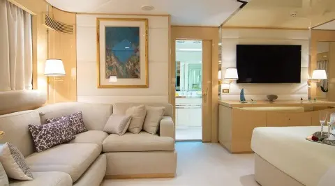 Luxurious yacht interior with beige couch, wooden cabinets, and flat screen TV