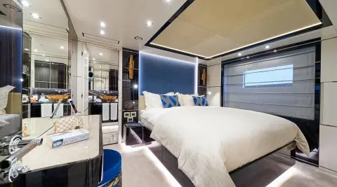 Luxurious yacht bedroom with large bed, blue accents, and warm lighting at sunset