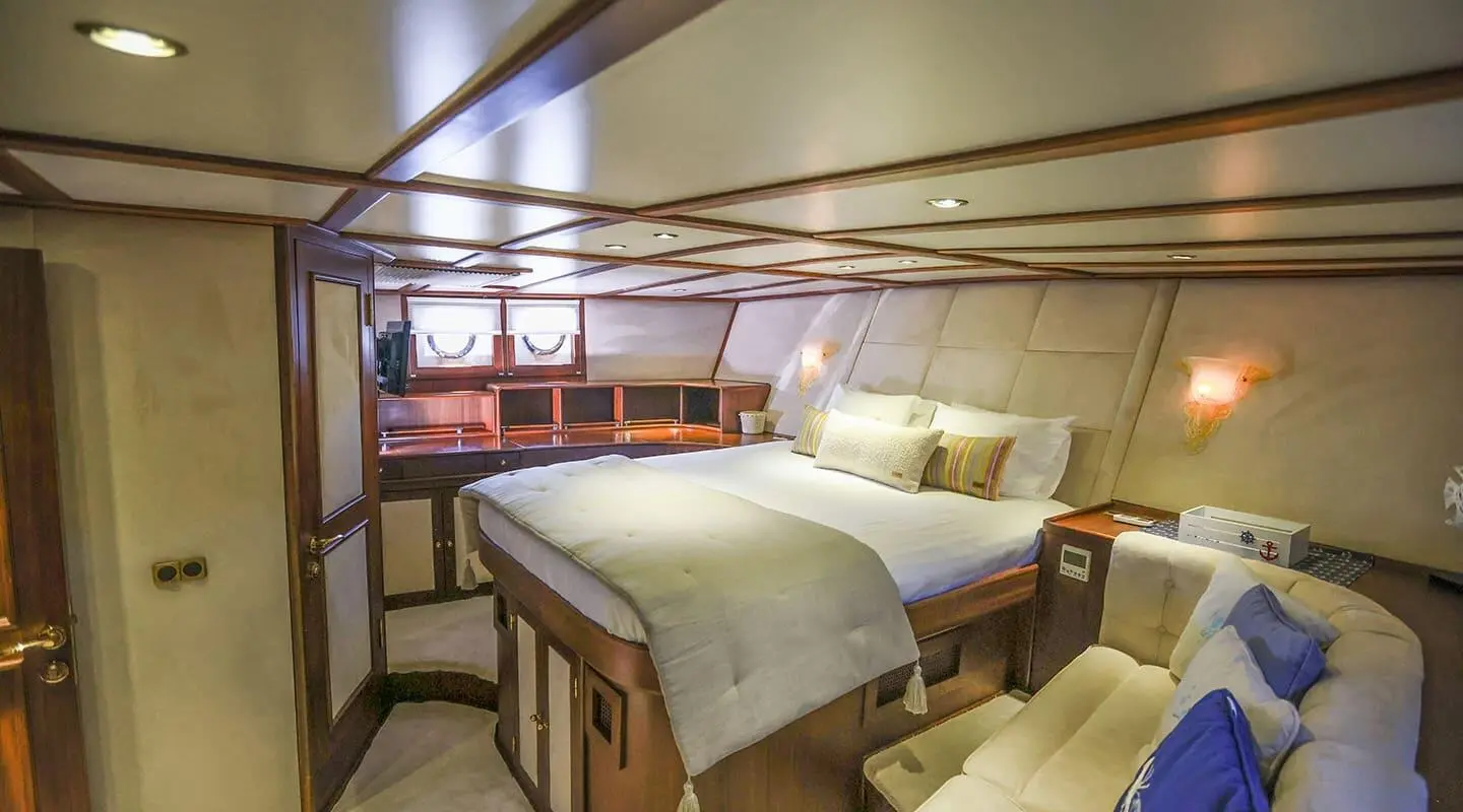 Gazella yacht interior with wooden framed beds and beige cushions at sunset