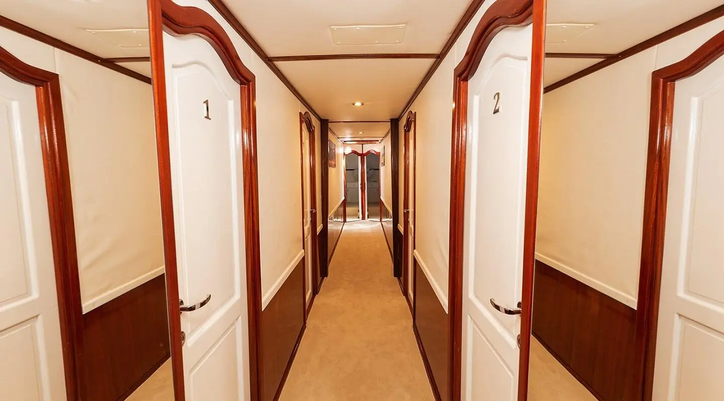 Interior hallway on Aurum yacht, warm wood panels, subtle lighting, corridor perspective