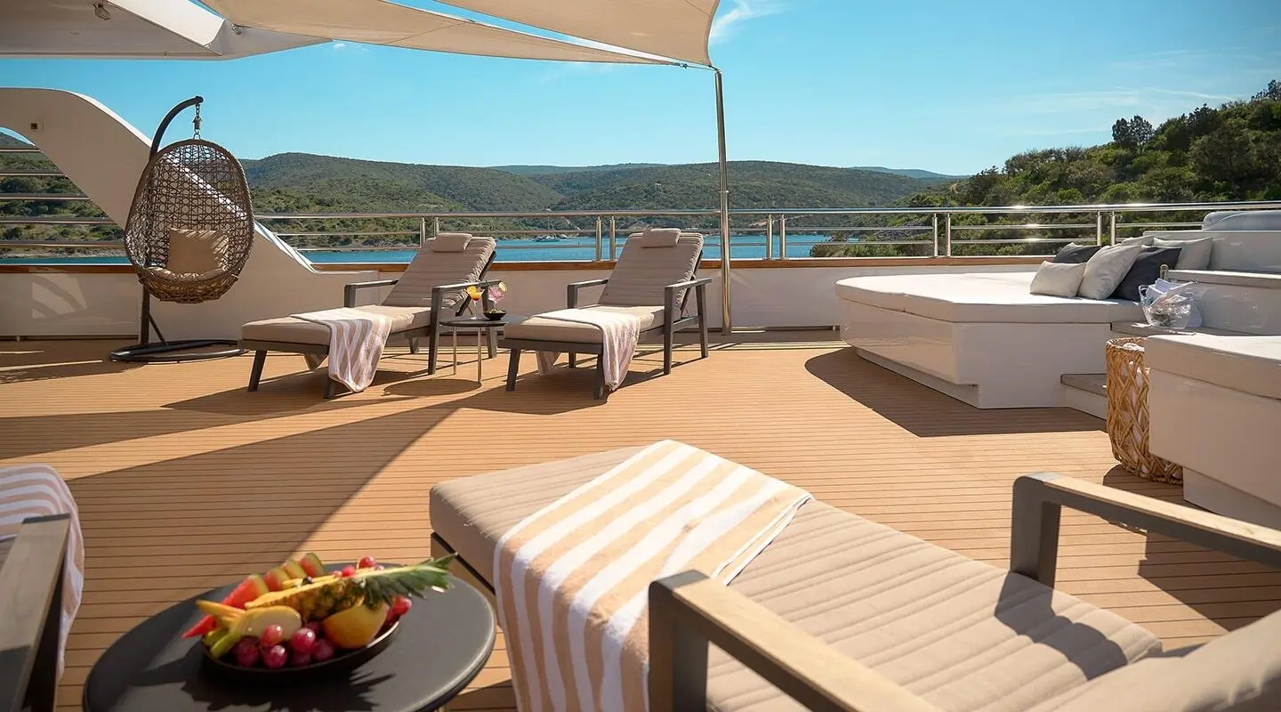 Upper deck on Cristal yacht with loungers and striped awning over sea view
