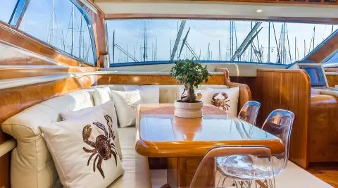 Aft seating area on Amoraki yacht with cushioned chairs and wooden table