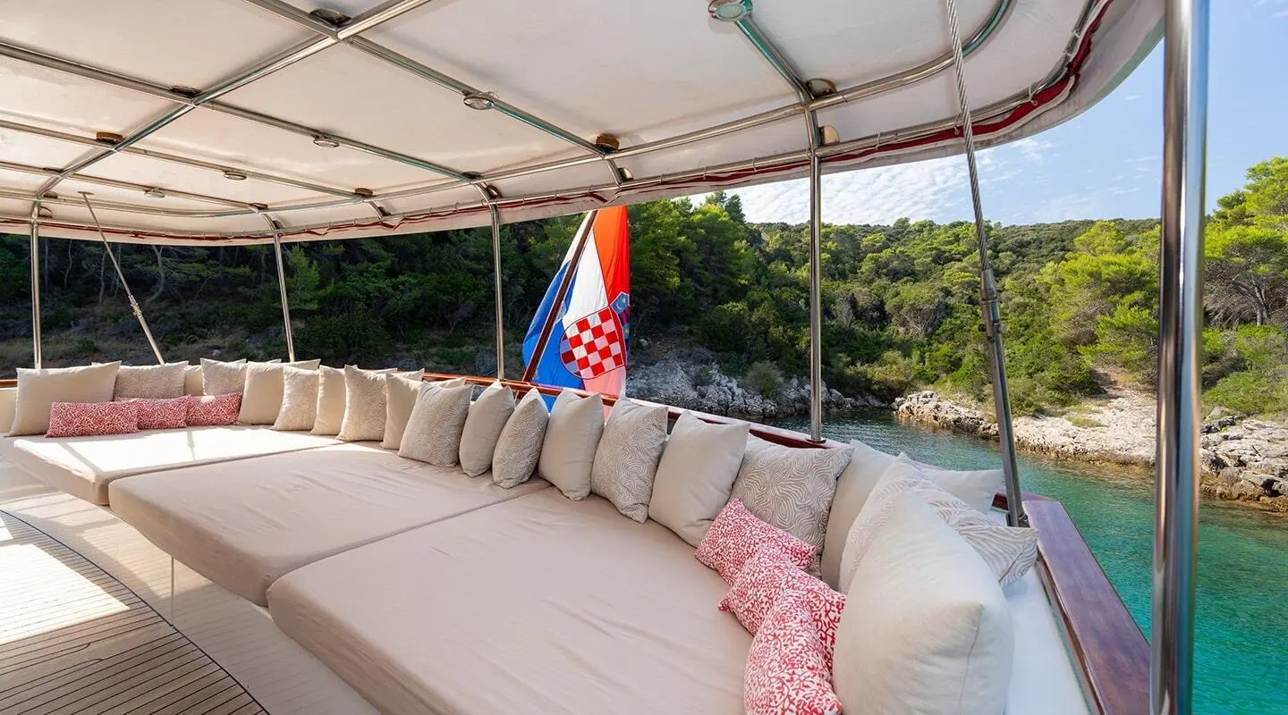 Yacht Barbara exterior seating area with cream cushions and pink throw under canopy