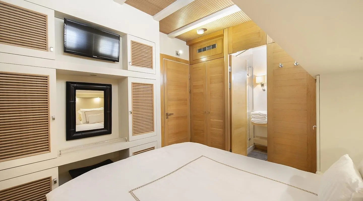 Interior of a cabin with wooden doors and wardrobes, bed and mirror
