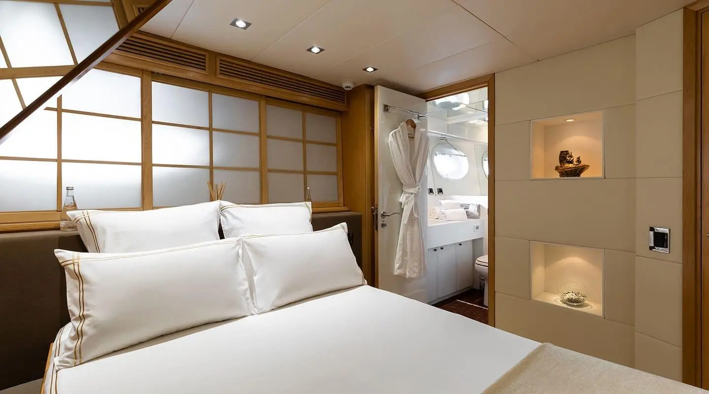 Brooklyn yacht bedroom with large bed, white linens, wooden panels, and ambient lighting