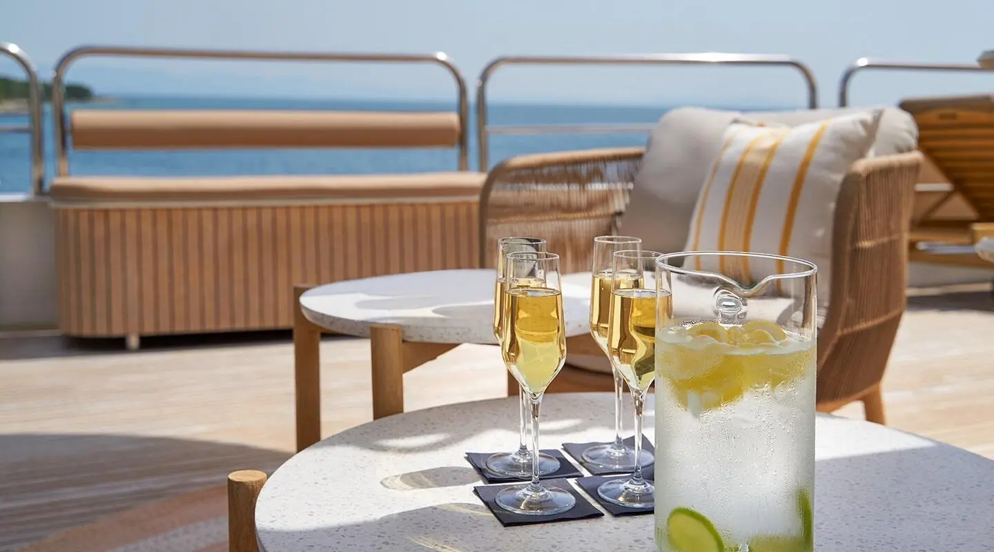 On deck with champagne flutes and a pitcher of lemon soda by seating area