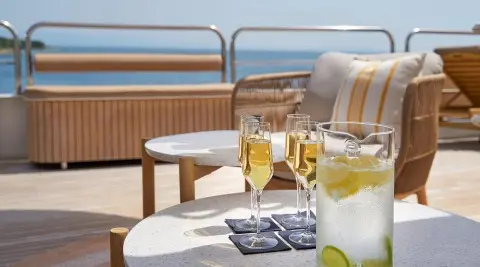 On deck with champagne flutes and a pitcher of lemon soda by seating area