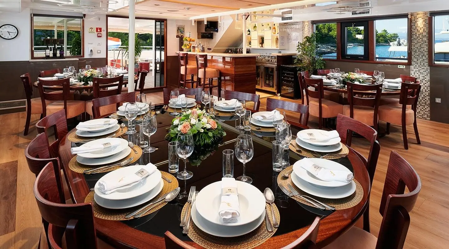 Queen Eleganza yacht dining area set for sunset with plates and glasses