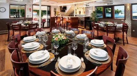 Queen Eleganza yacht dining area set for sunset with plates and glasses