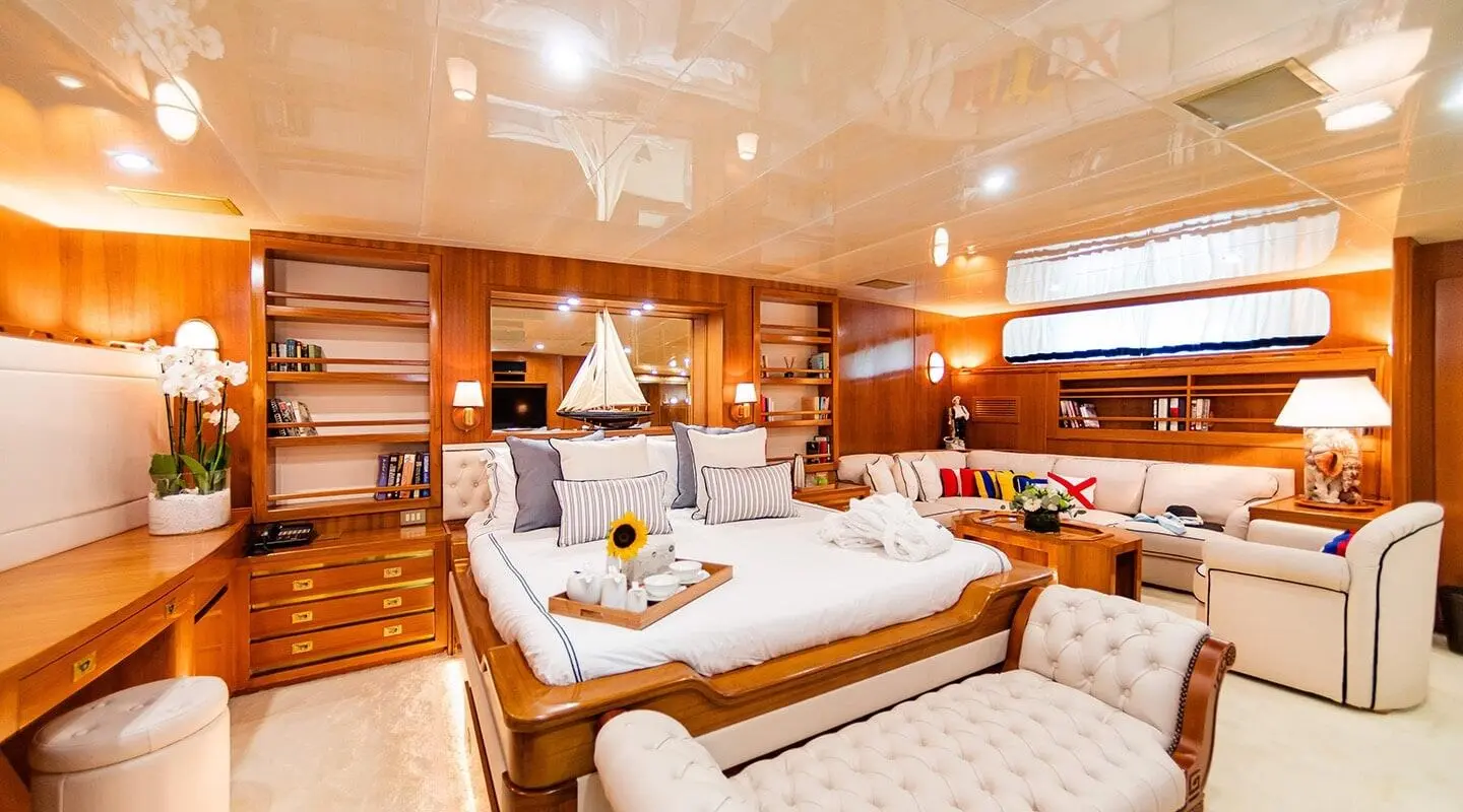 Interior of a wood-paneled yacht cabin with a bed and seating area