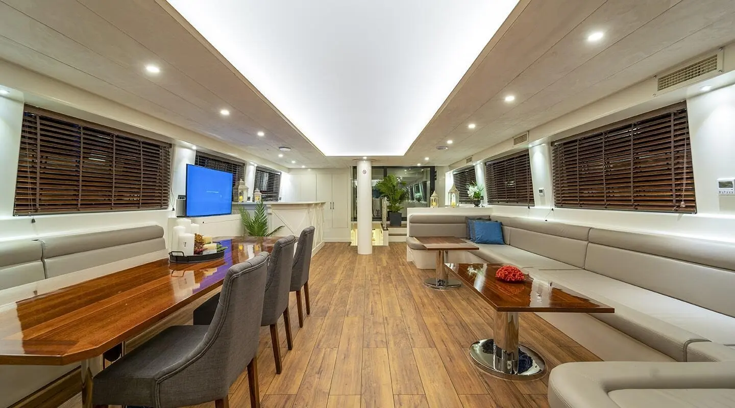 Luxurious interior of Queen Of Makri yacht with seating, tables, and polished wood deck