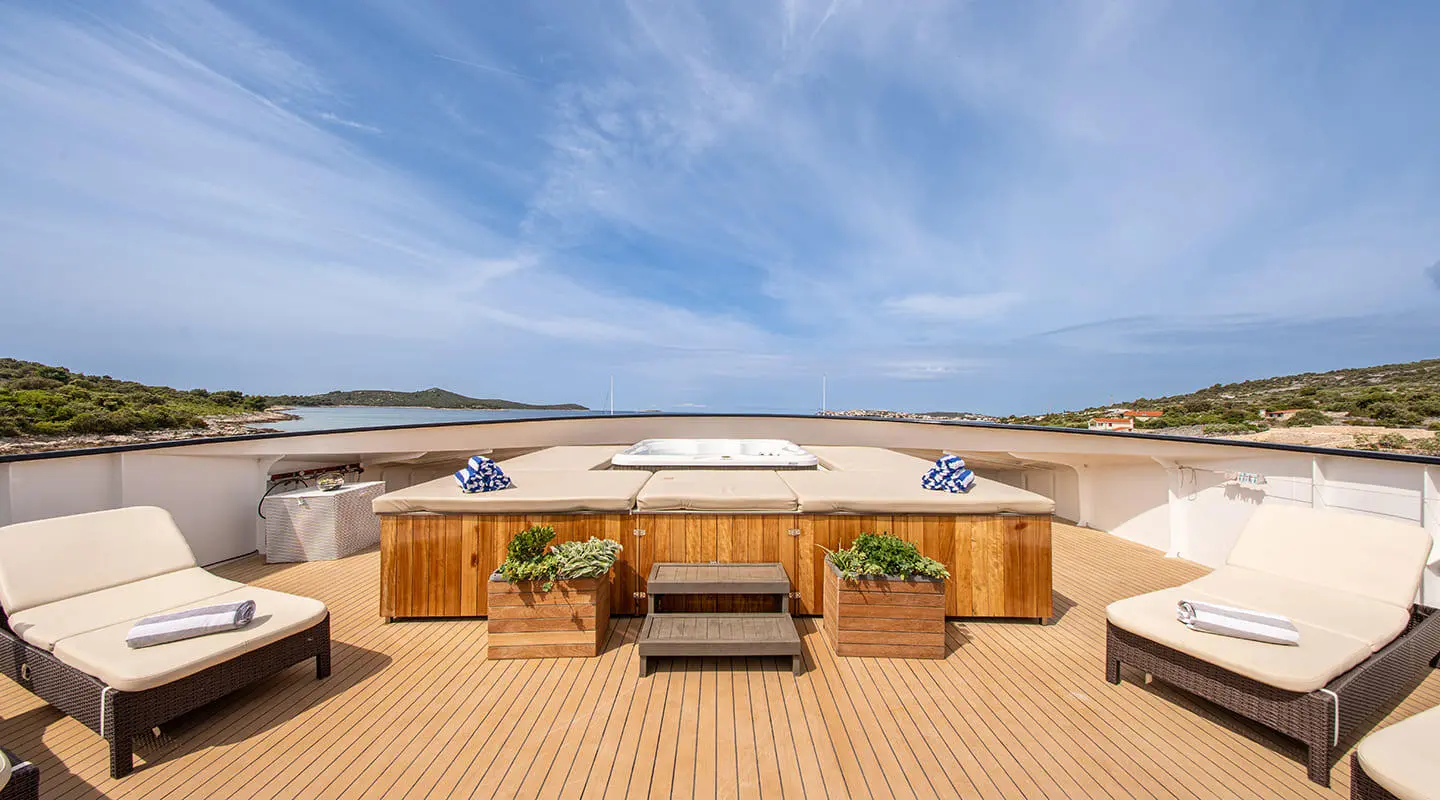 Karizma yacht sundeck with seating, wooden decking, ocean view under blue sky