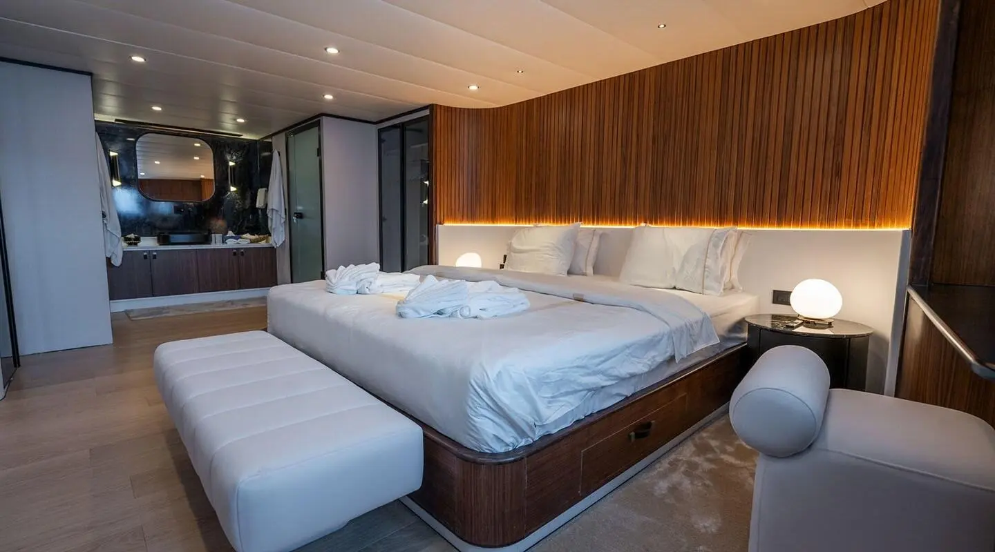 De Love yacht bedroom with two single beds, wood paneling, soft lighting, and porthole view