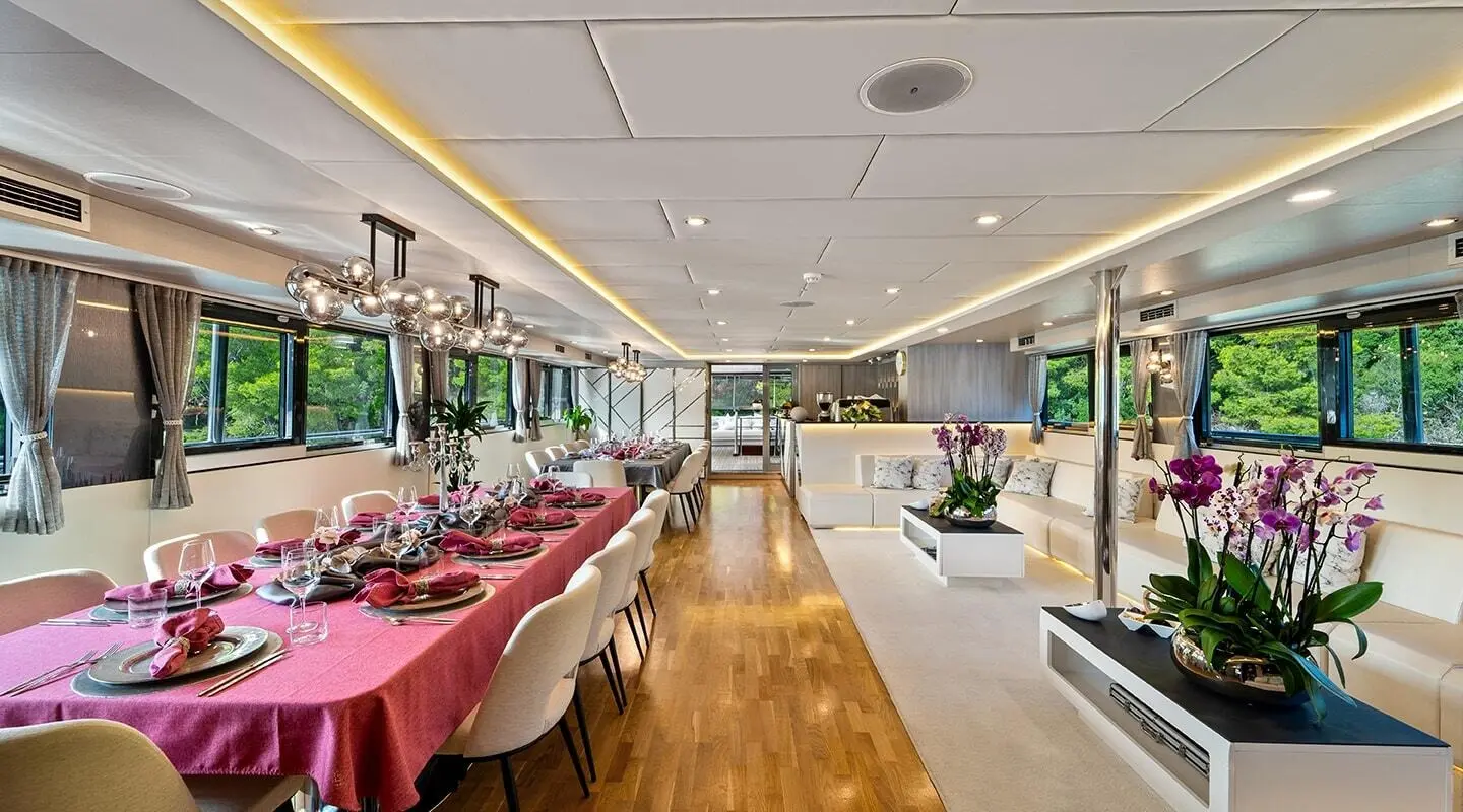 Interior of Freedom yacht saloon with dining table, chairs, and bright lighting