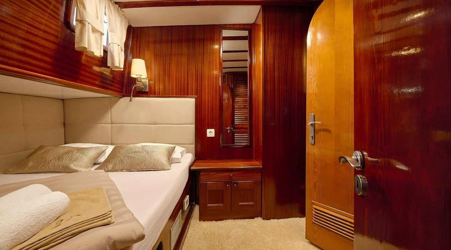 Cozy yacht interior with wooden cabinet, bed, and open doorway at sunset