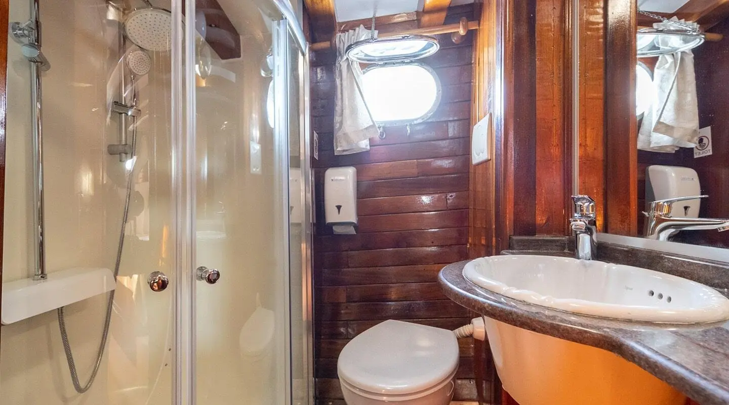 Interior of a yacht with wooden panels, sink, and shower stall