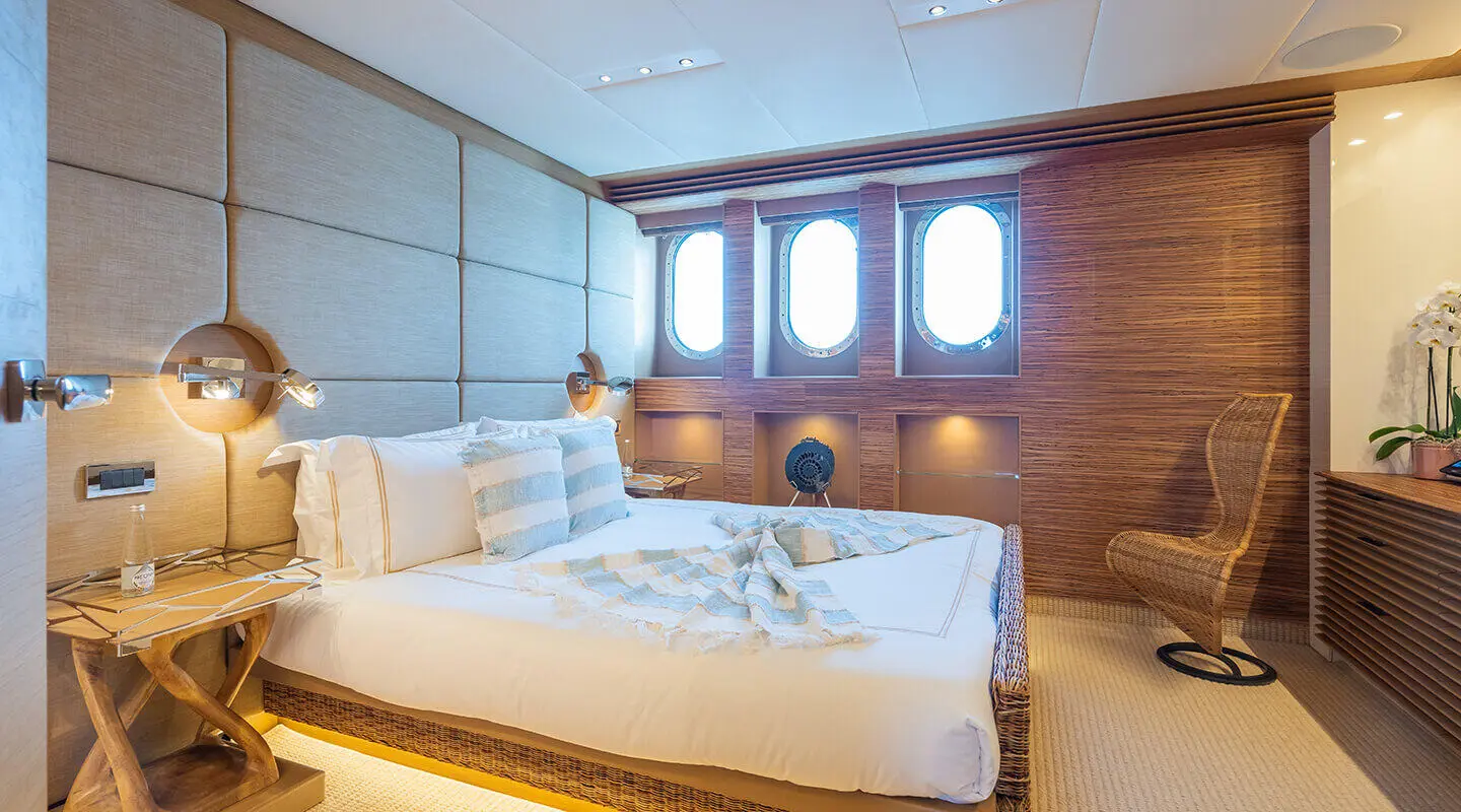Hotel-style bedroom on a yacht with padded headboard walls and wooden accents
