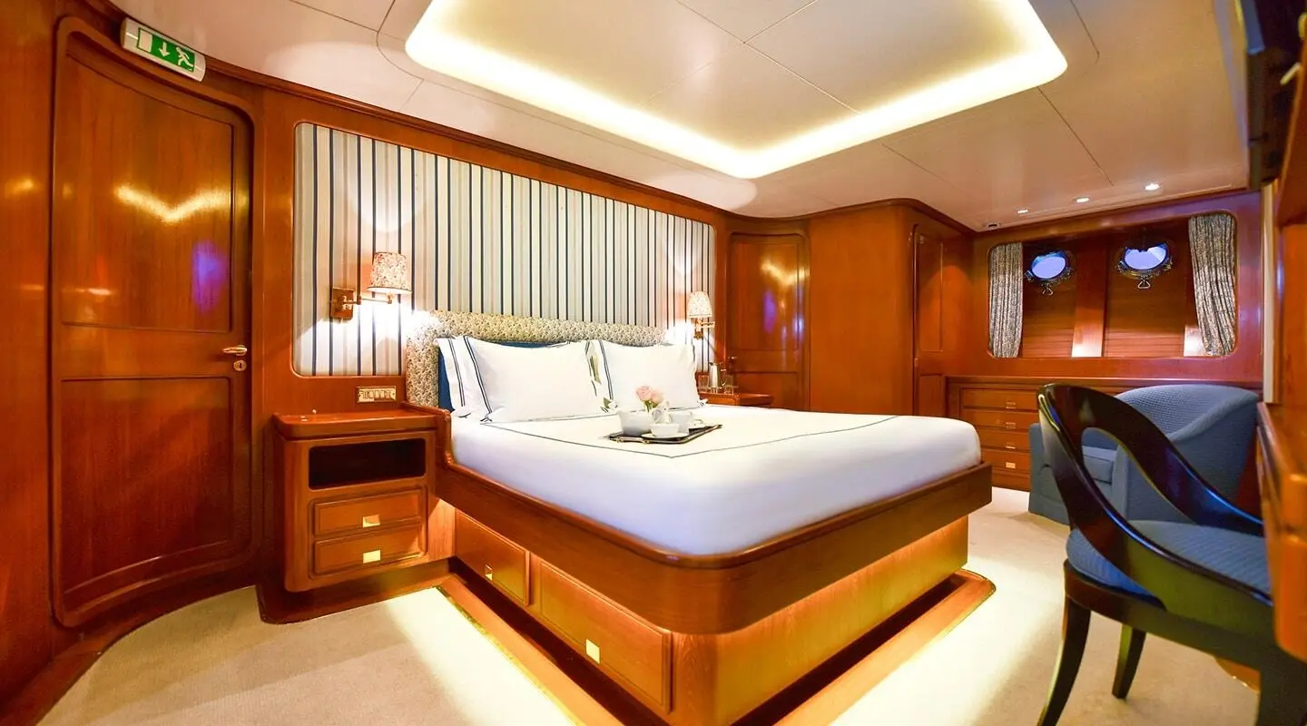 Tamarita yacht bedroom with polished wood, large bed, and ambient lighting