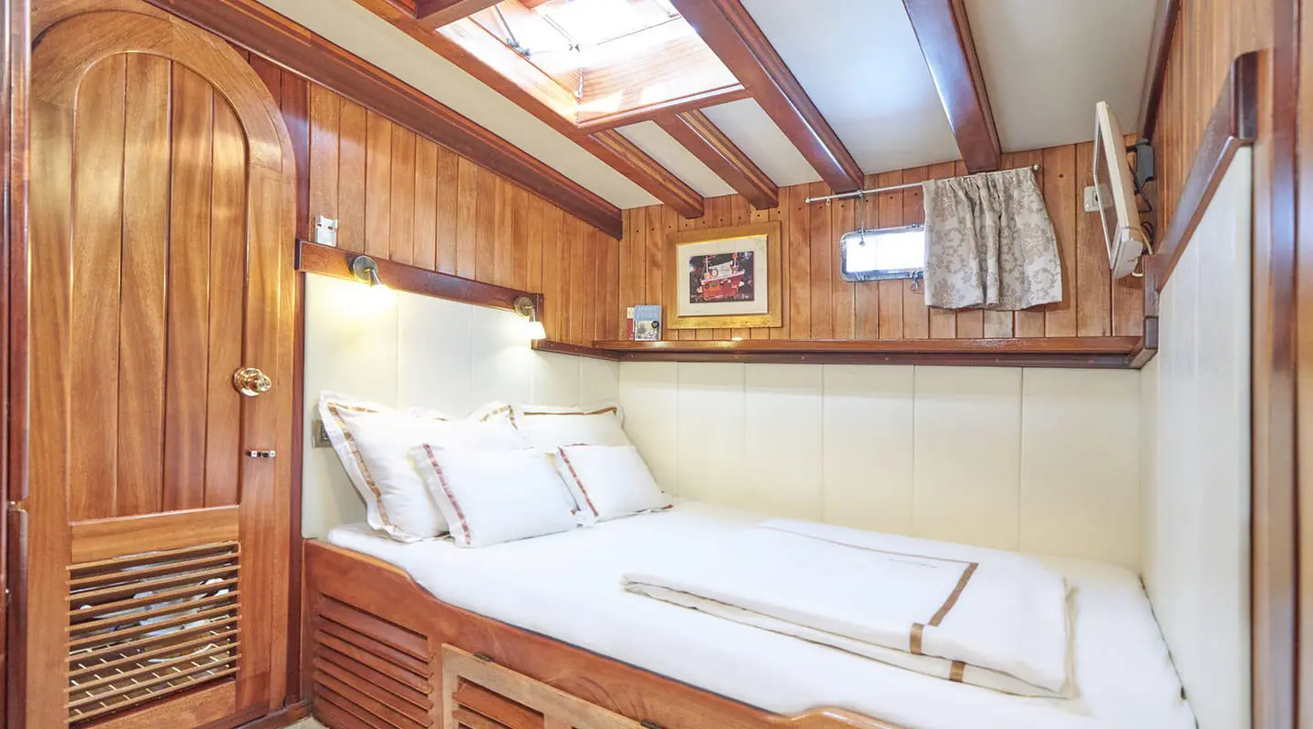 Gulet Libra interior cabin with bed and wooden walls, soft lighting