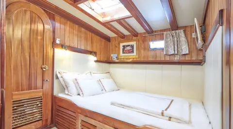 Gulet Libra interior cabin with bed and wooden walls, soft lighting