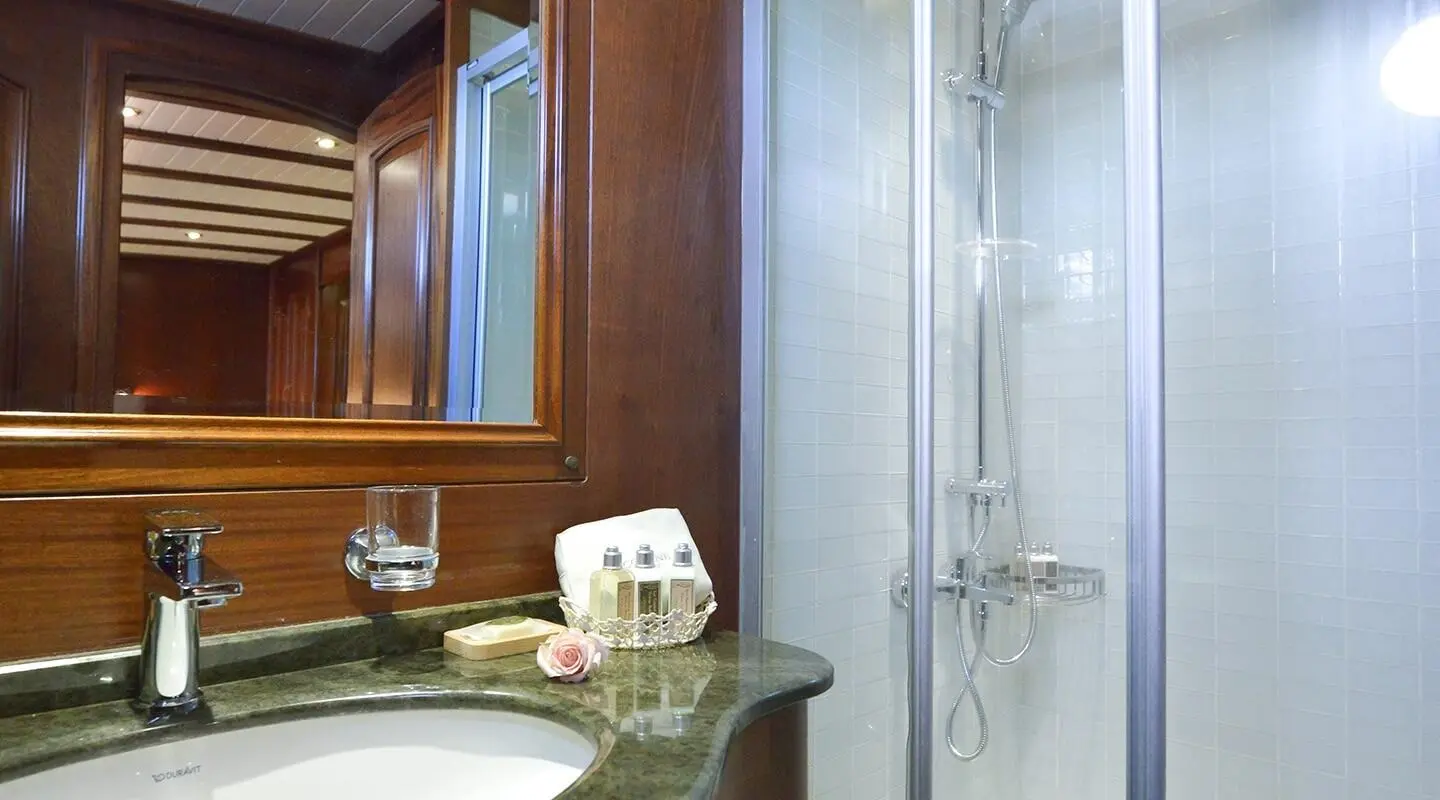 Bathroom on Lady Christa gulet with wooden vanity, mirror, towels, and shower
