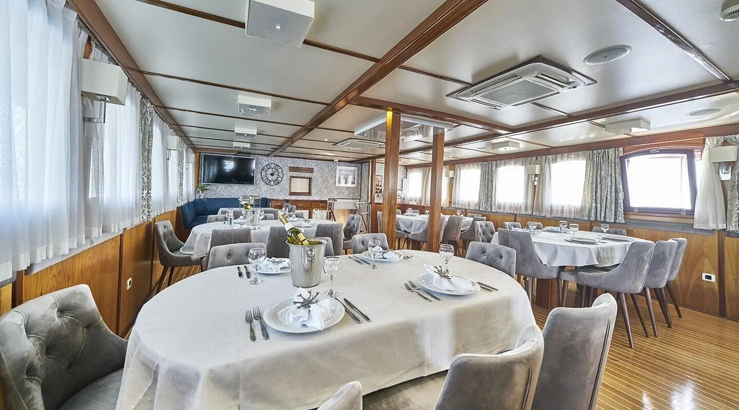 Interior of Amorena yacht saloon with dining table set and large windows