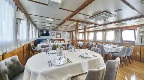 Interior of Amorena yacht saloon with dining table set and large windows