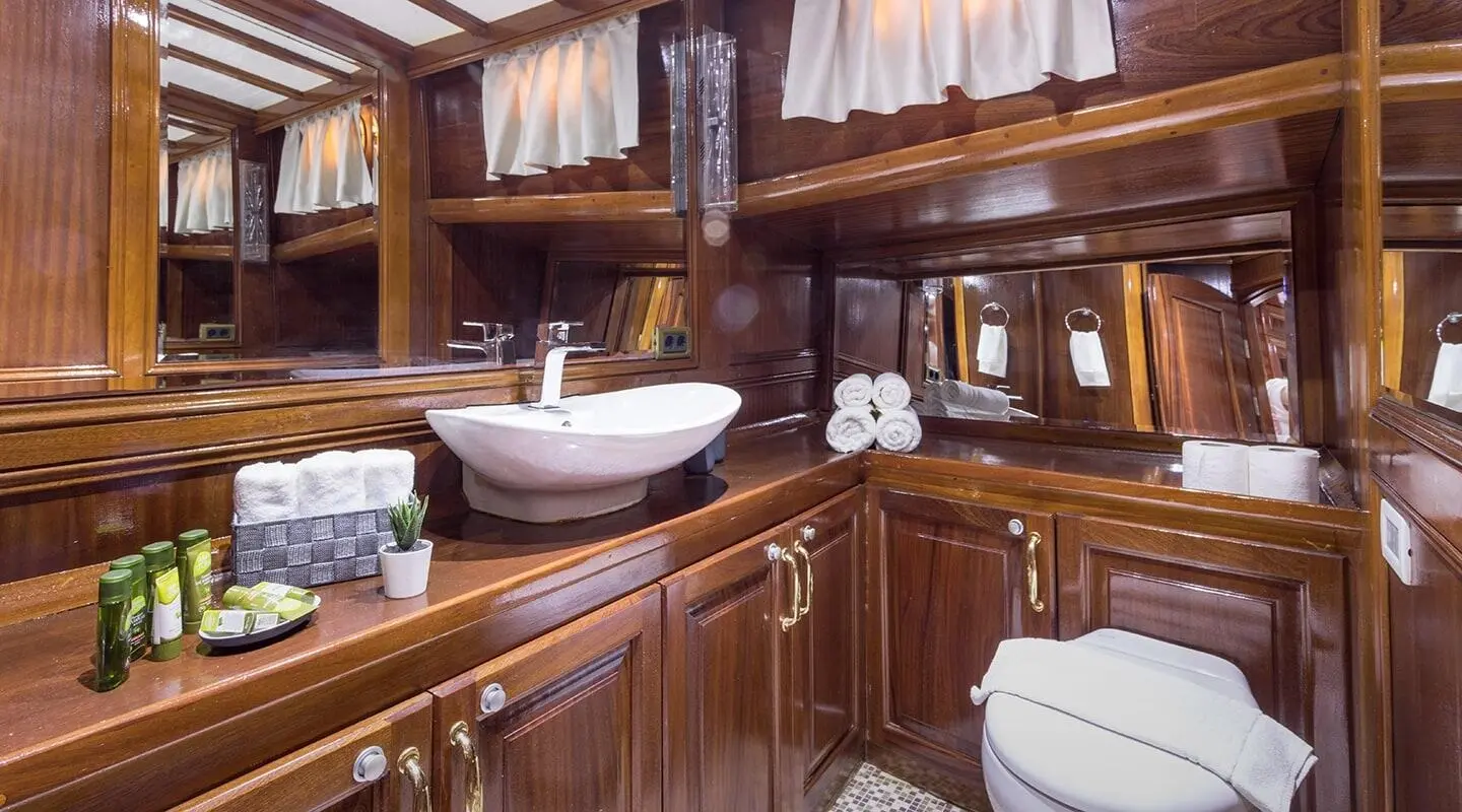 Grace 1 gulet interior with wooden cabinetry, a sink, and towels in a bathroom
