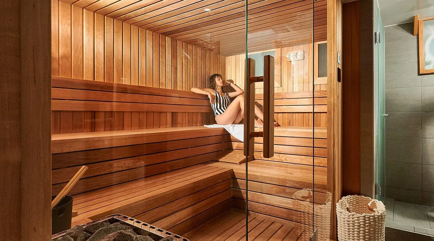 Woman in swimsuit reclining on wooden sauna bench inside a yacht sauna
