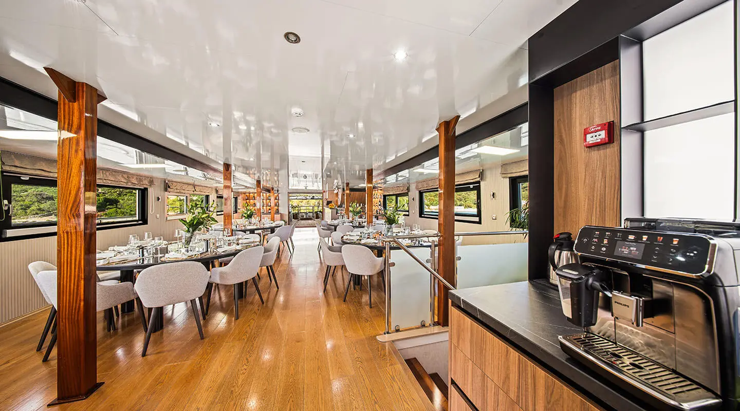 Interior of Karizma yacht saloon with wooden flooring, seating, and tables