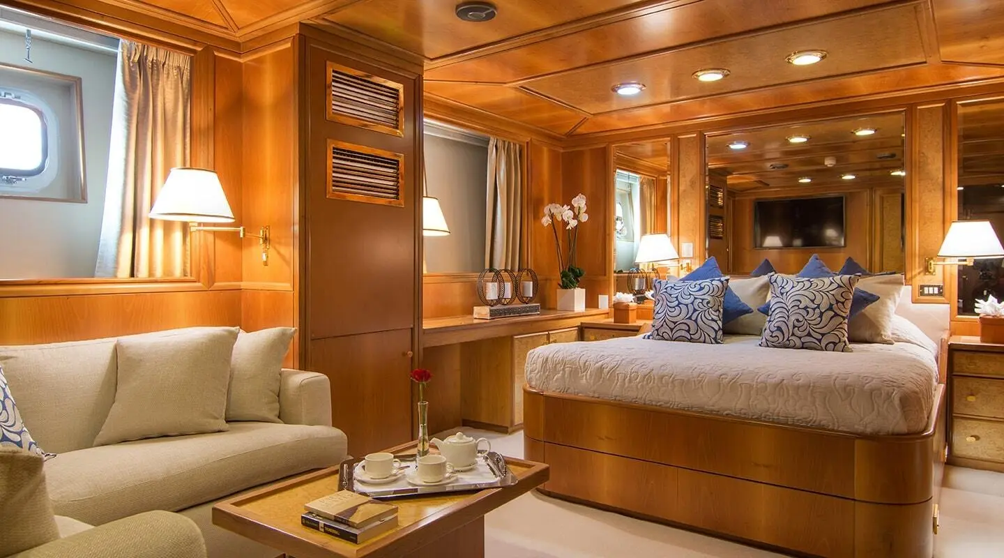 Luxurious yacht interior with polished wood panels, seating, and a bed visible