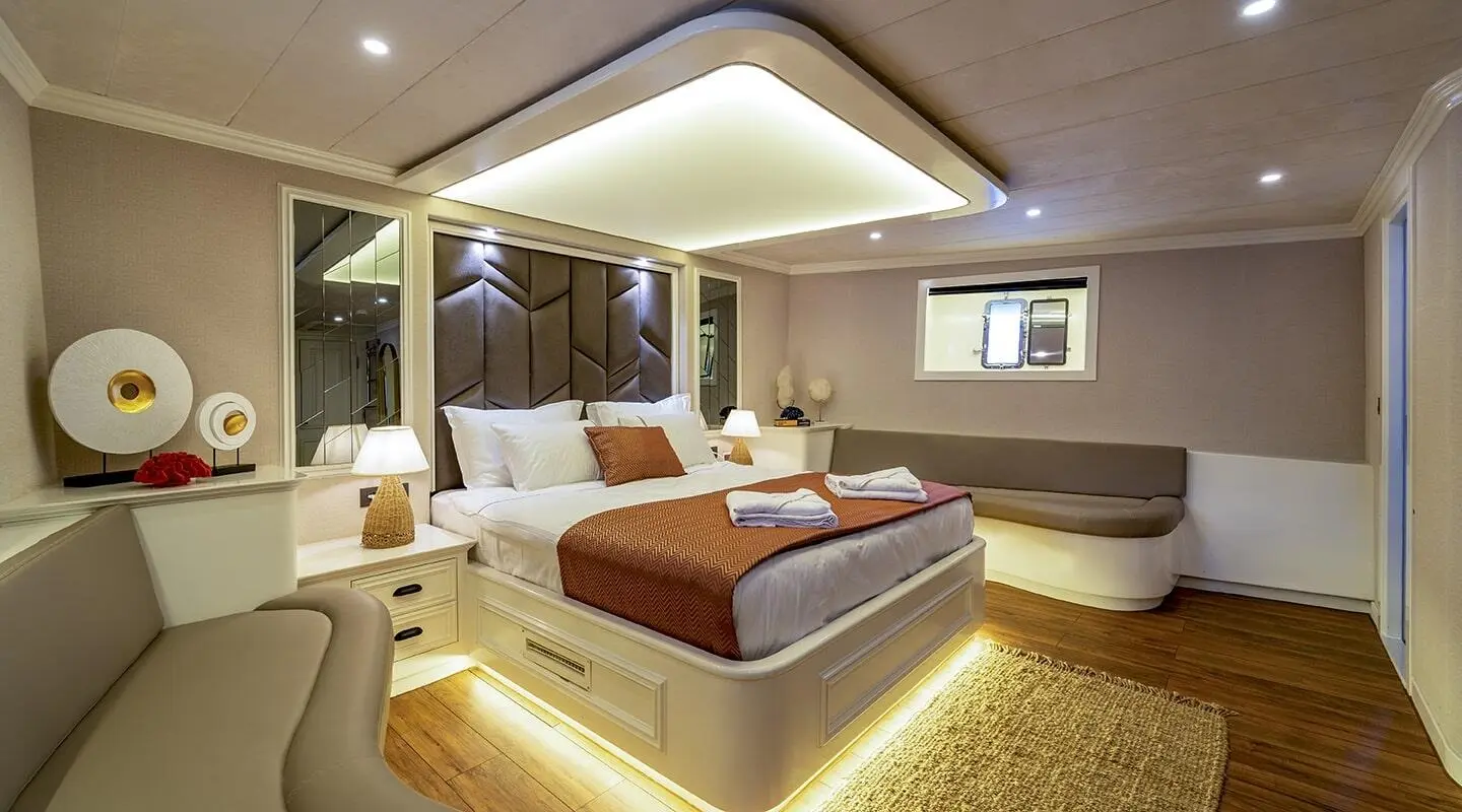 Luxurious Queen Of Makri master cabin with king bed, soft lighting, and stylish seating