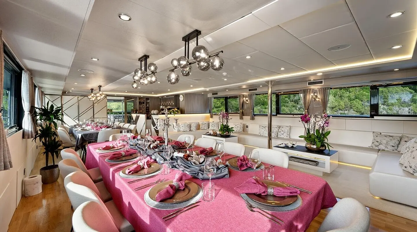 Luxurious indoor dining on a pink table set aboard a yacht, chandelier-lit