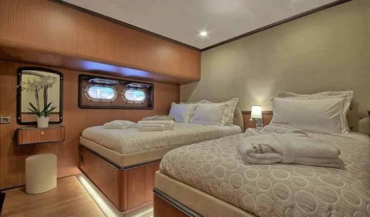 Queen Of Salmakis cabin interior with two single beds and warm lighting