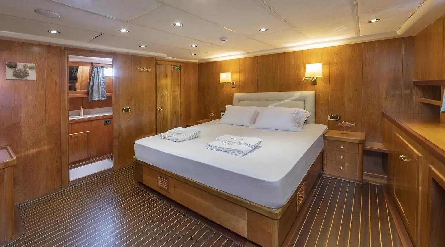 Queen Of Sea yacht interior with wooden walls, large bed, warm lighting