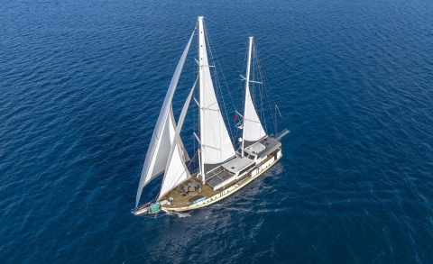 Luxurious sailing gulet with tall white sails on a deep blue sea