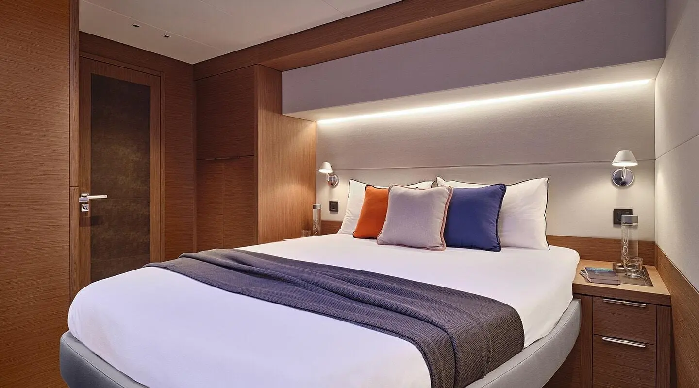 Daiquiri motor yacht cabin with bed, pillows, and wood interior