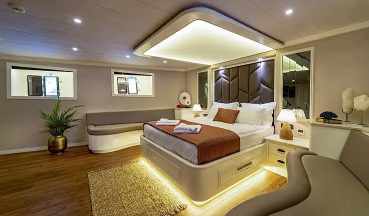Queen Of Makri master cabin with king bed, ensuite, warm lighting, panel walls