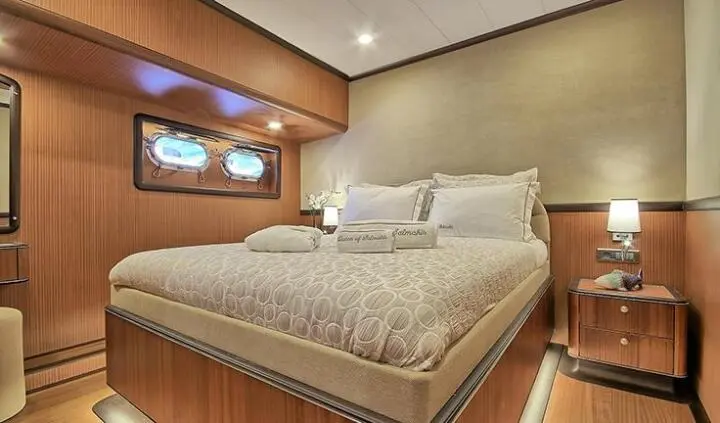 Queen Of Salmakis master cabin: neatly made bed with portholes and wood paneling
